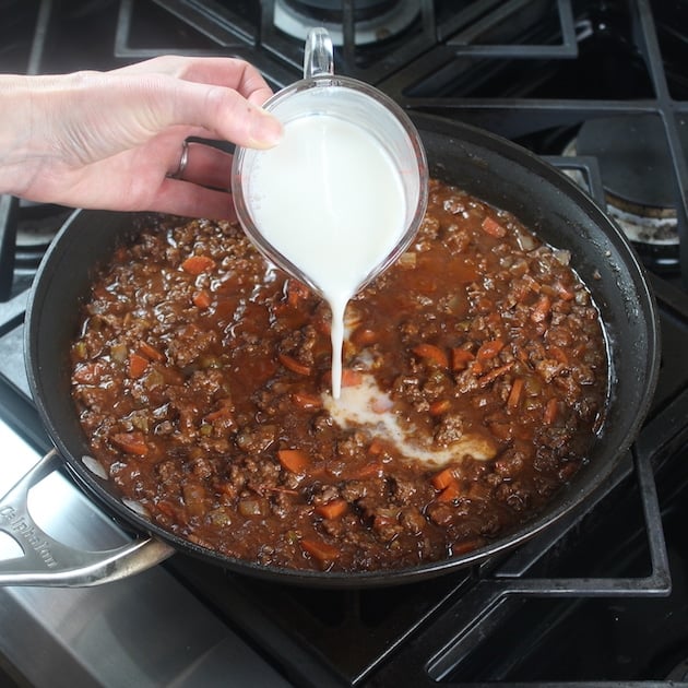 Adding milk to saute pan of bolognese sauce