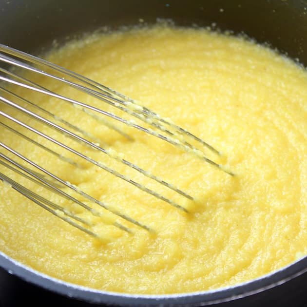 Close up of wire whisk in pot of polenta