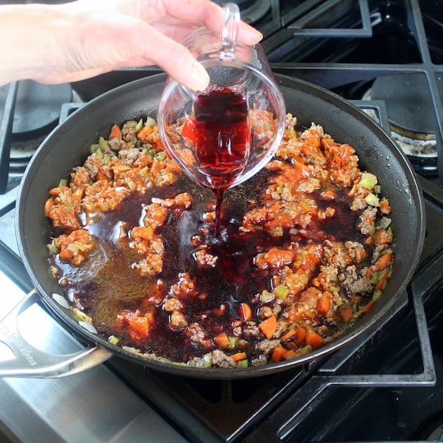 Adding red wine to bolognese cooking on stovetop