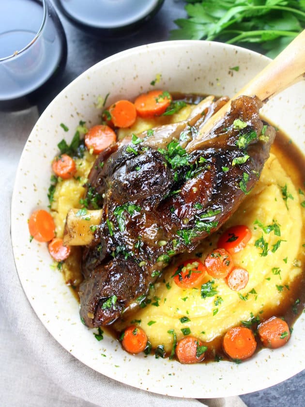 Slow cooked glazed lamb shank in a bowl of parmesan polenta with cooked carrots