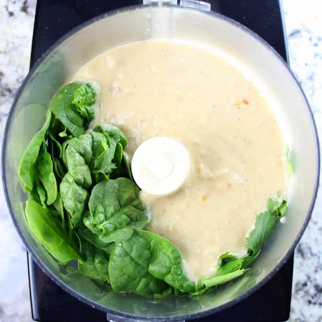 Creamy sauce in food processor with greens ready to mix in