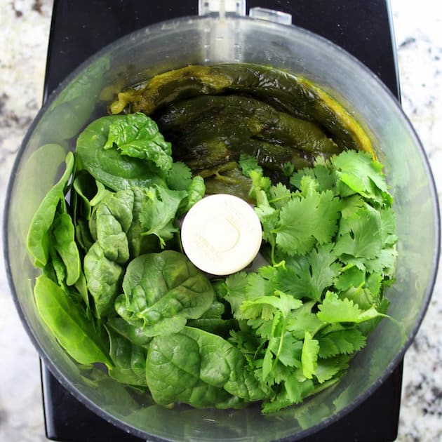 Greens and cilantro in a food processor ready to mix 