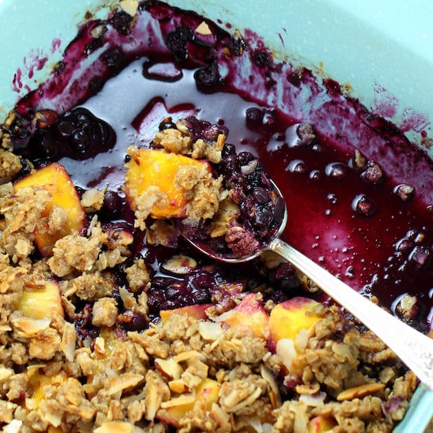Spoon in a baking dish of Blueberry Mango Crumble 