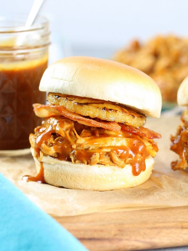 A sandwich sitting on top of a wooden cutting board, with Chicken and Bacon