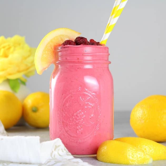 Pink smoothie in mason jar with yellow and white striped straws