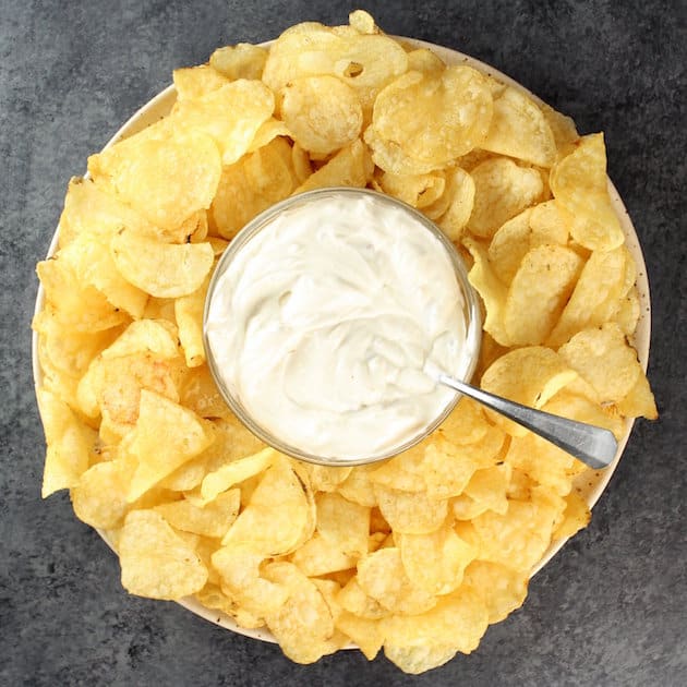 Classic potato chips on platter with bowl of onion dip in the middle
