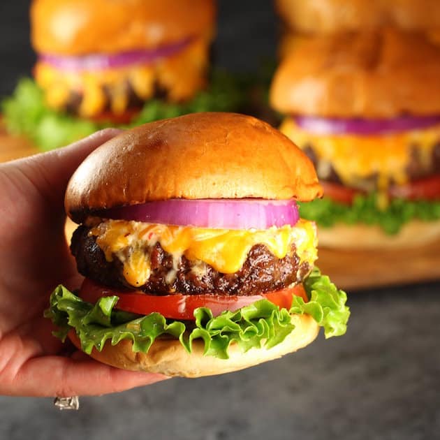 Hand holding a bacon cheeseburger