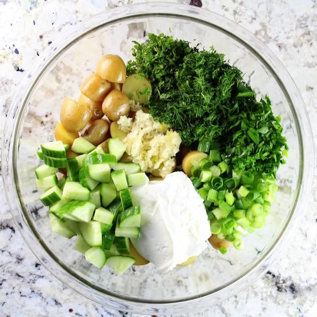 Bowl of ingredients for potato salad in a large glass mixing bowl