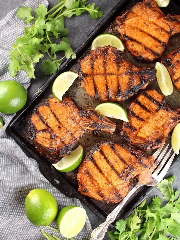 Maple Sriracha Grilled Bone-In Pork Chops  surrounded by limes and cilantro