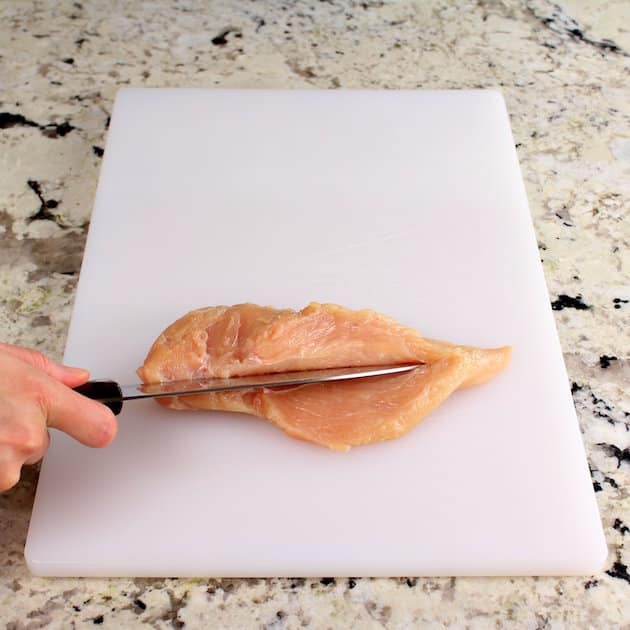 Slicing a chicken breast on a cutting board