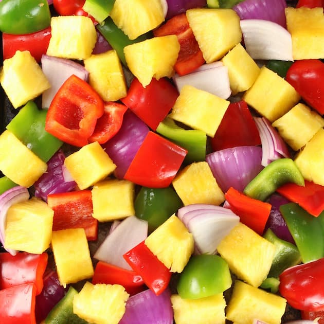 Closeup of chopped fresh pineapple, red &amp; green peppers, and red onions.