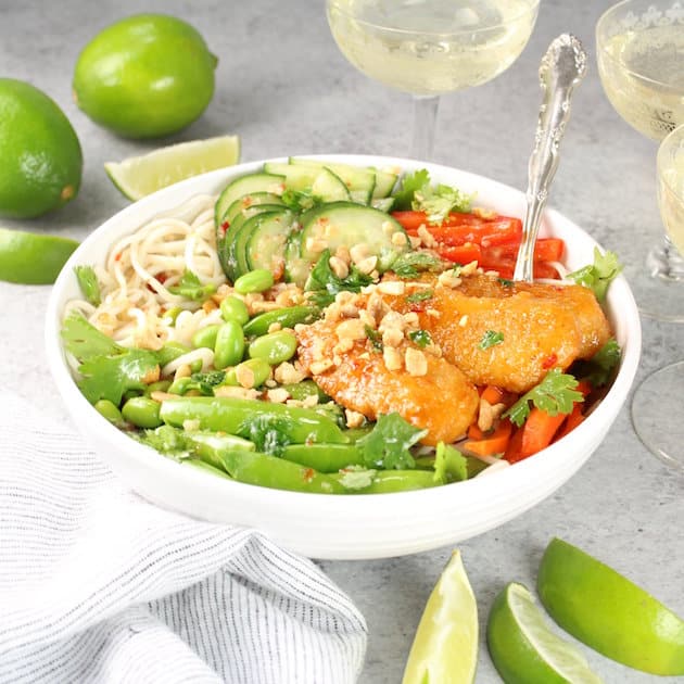 Thai noodle fish bowl with limes and wine glasses