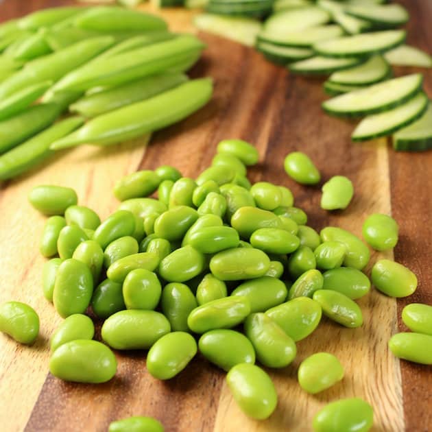 Edamame, Snap Peas, and Cucumbers on a cutting board