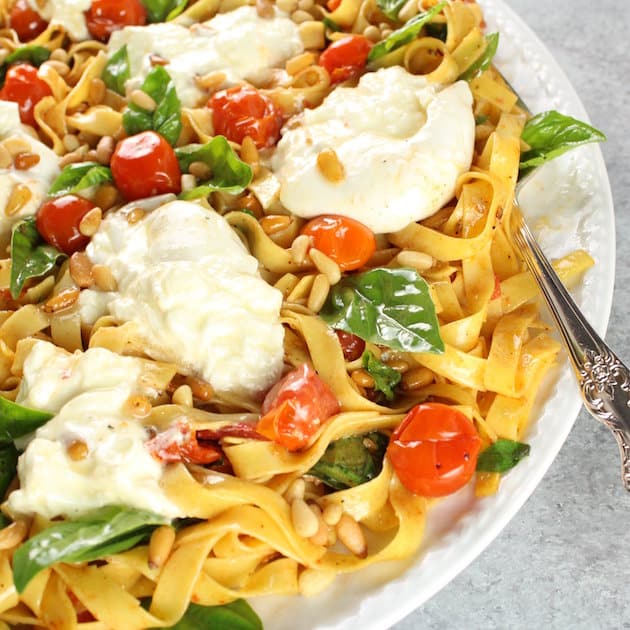 Partial Platter of pasta noodles with fresh mozzarella, tomatoes, Basil, and Pine Nuts