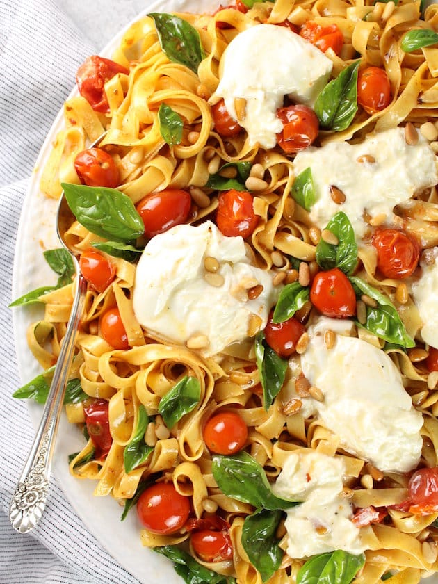 Partial platter of egg noodles, tomatoes, basil, and fresh mozzarella