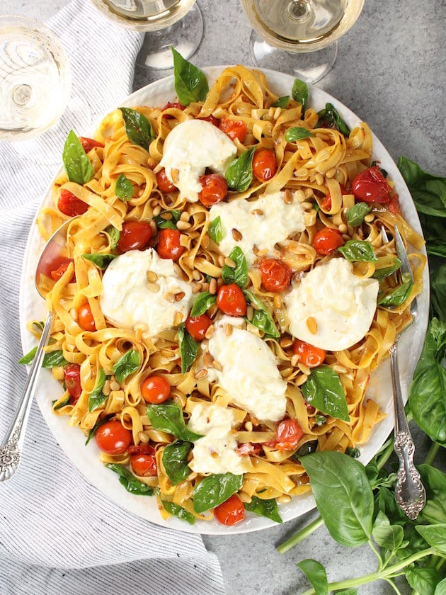 Platter full of Tagliatelle Noodles with Burrata Cheese, Tomatoes, and Pine Nuts