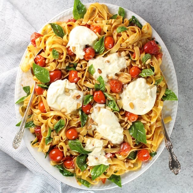 Platter of tagliatelle pasta with tomato, burrata, and basil