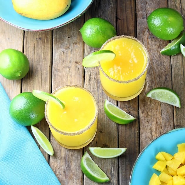 Smoky Mango Margaritas on farm table with limes and mangos