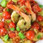 Closeup of shrimp in pesto sauce on tomato polenta bed