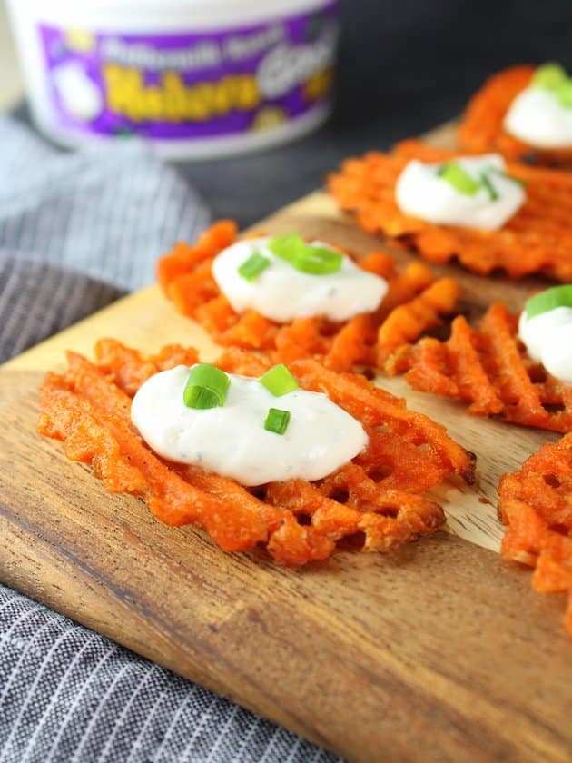 Sweet potato waffle fries on a cutting board with cheese dip