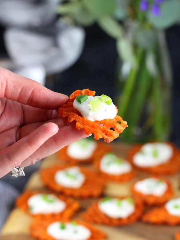 Hand holding sweet potato waffle fry with cheese dip