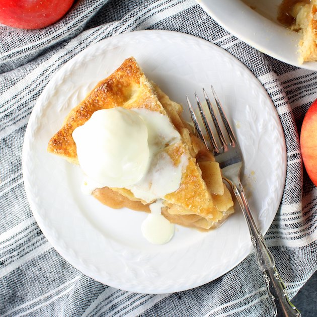 A piece of Caramel Apple Pie with a scoop of vanilla ice cream on top.
