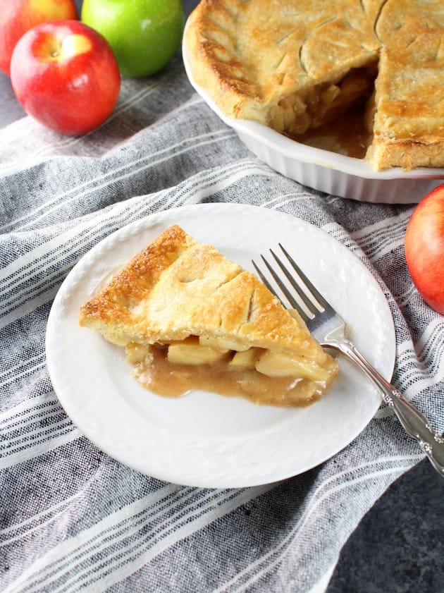 Eye level view of Caramel Apple Pie with slice cut out on a plate.