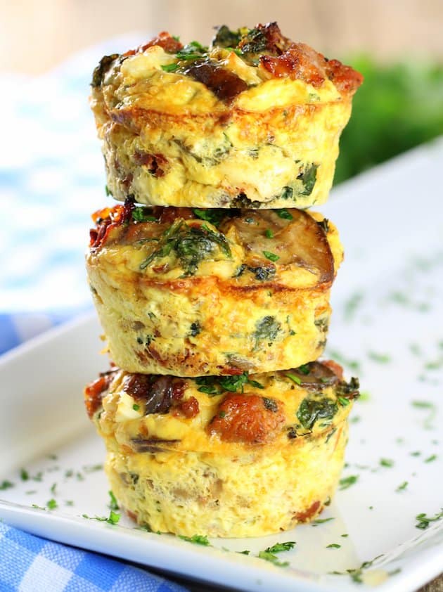 Three healthy kale egg breakfast cups stacked on top of each other on a platter.