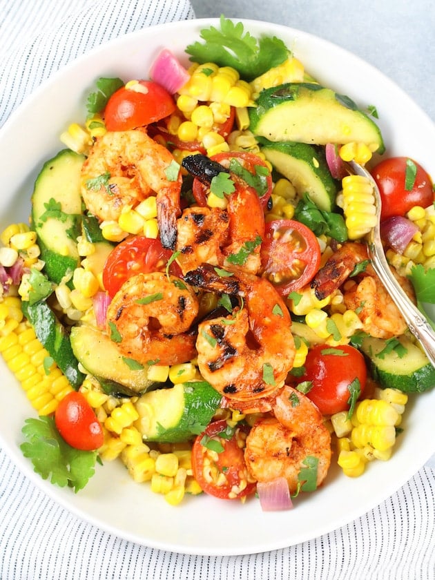 A plate is filled with food, with Corn salad