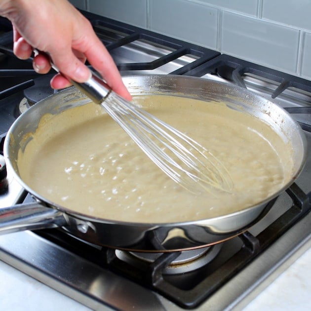 WHisking creamy Mushroom sauce in saucepan