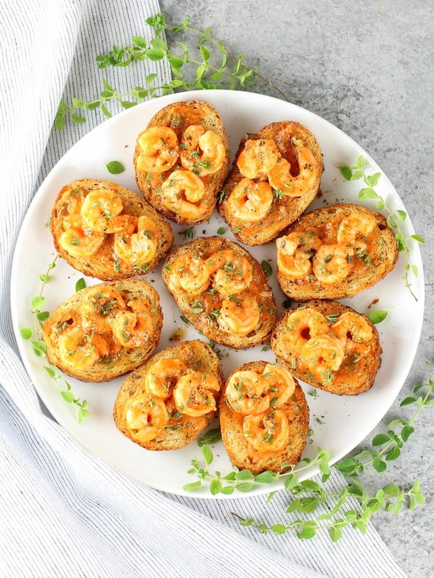 A platter of one bite appetizers including deviled eggs, stuffed mushrooms, and bruschetta with vibrant toppings.