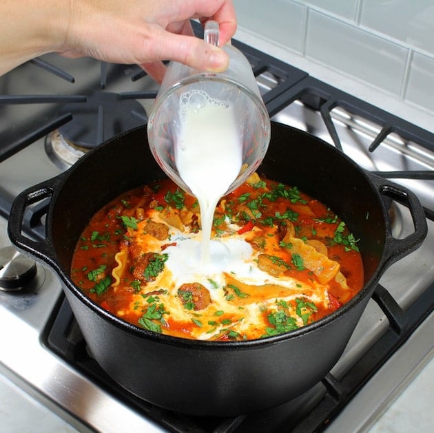 Adding half and half to pot of chicken sausage lasagna soup