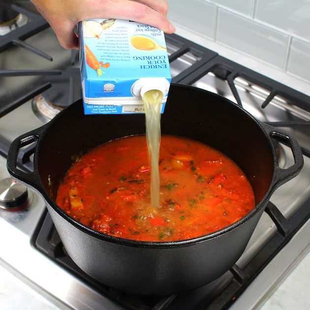 Adding chicken stock to pot of soup on stovetop