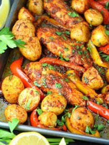 Close up sheet pan of harissa chicken potatoes and bell peppers