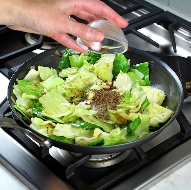 Adding salt and pepper to pan of cabbage