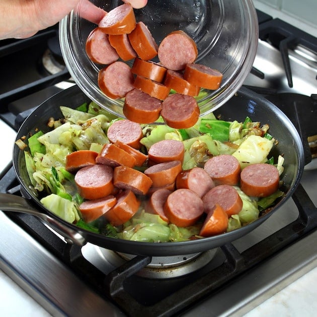 Adding Kielbasa Into Pan of cabbage