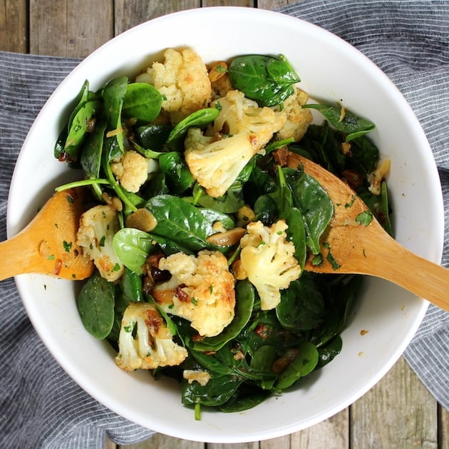 Warm Cauliflower Spinach Salad with wooden tongs