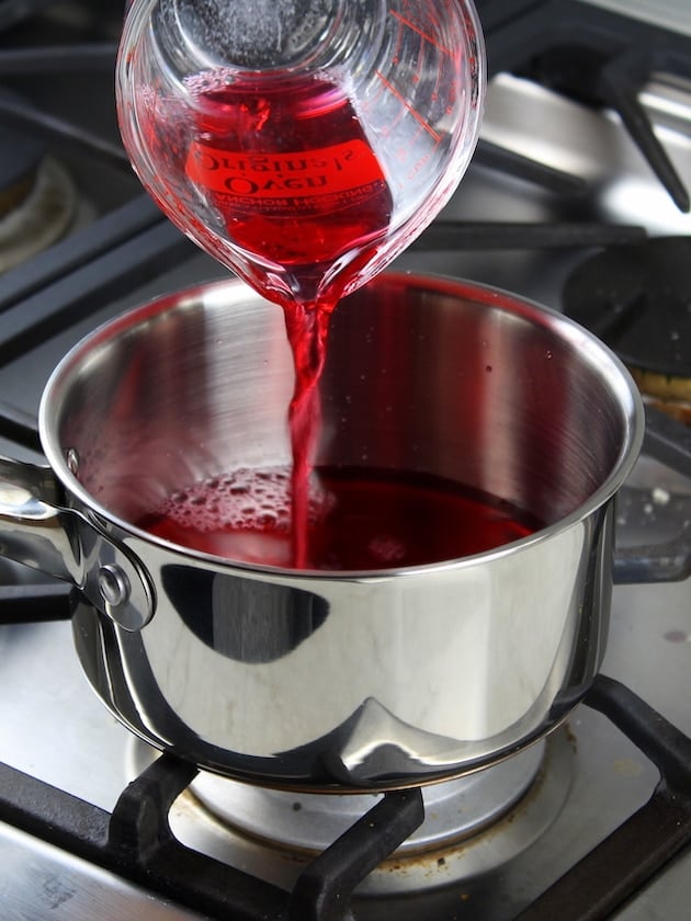 Adding cranberry juice to cooked cranberries on stove