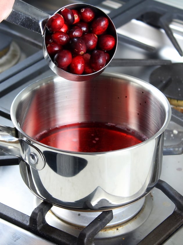 Adding cranberries to saucepot on stove