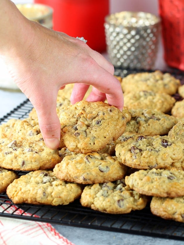 A person picking up a cookie from the cooling rack.