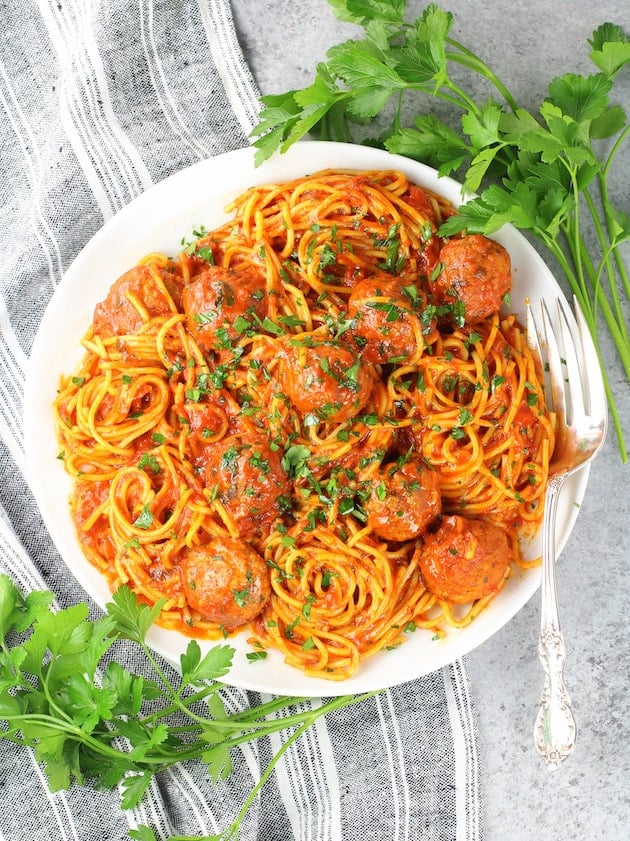 A bowl of pasta on a plate with Meatballs