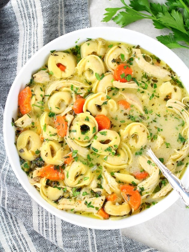 A bowl of tortellini soup with chicken