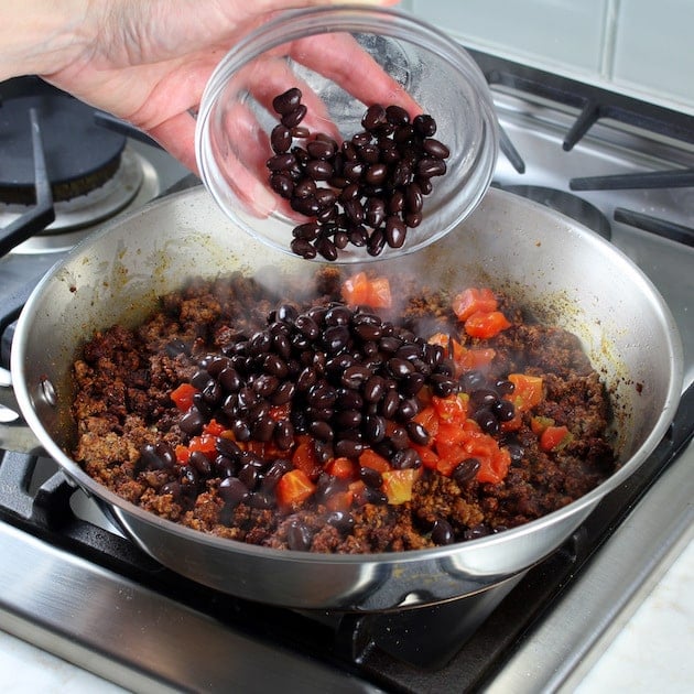 Adding Black Beans to ground beef and seasoning.
