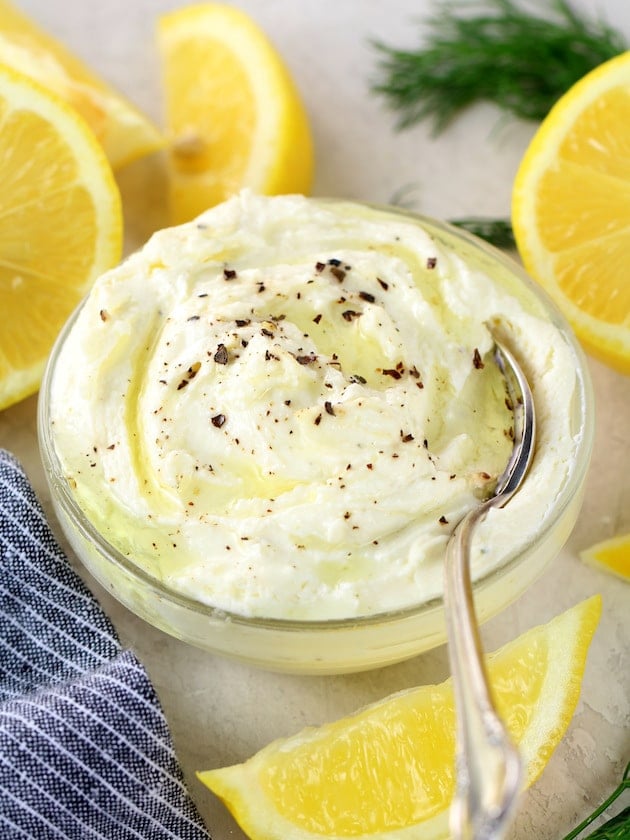 Whipped Feta Cheese Spread in a glass bowl, with lemons in background