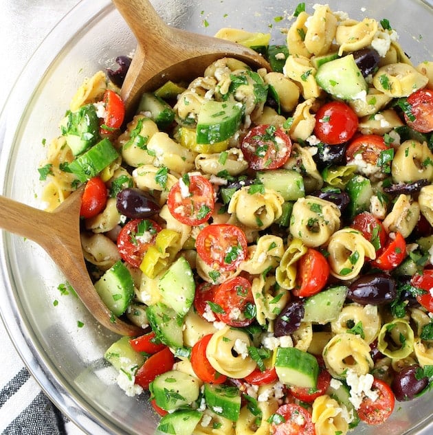 A colorful bowl of summer salads featuring summer pasta salad, summer fruit salad, and a summer strawberry salad with fresh ingredients.