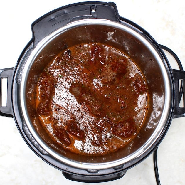 Chuck roast, cooking liquid and seasonings before pressure cooking.