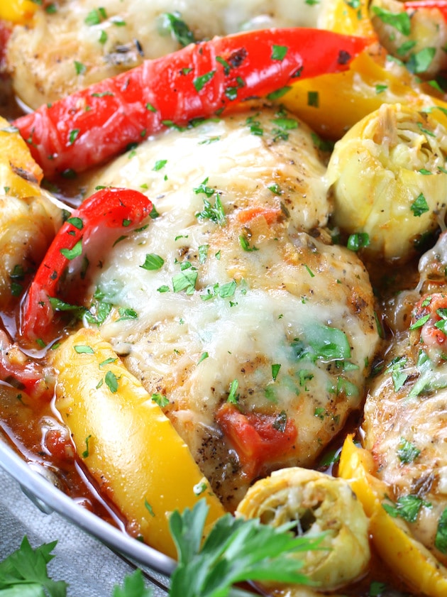 A close up of chicken breast in sauce with melted cheese
