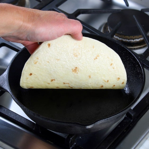 toasting a tortilla in a cast iron skillet