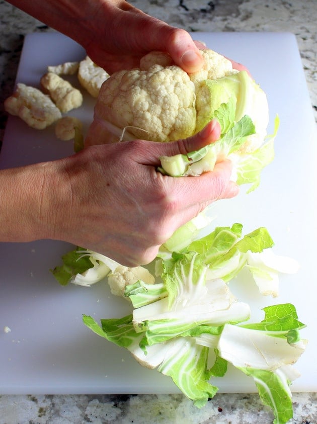 Peeling leaves off a head of cauliflower