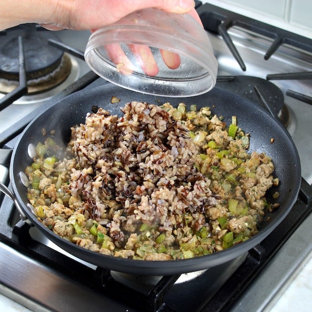 Adding wild rice to stuffing mixture in saucepan on stovetop